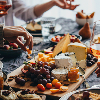 charcuterie board with hands eating holding wine glasses